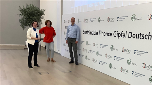 Die Organisator:innen Yvonne Zwick, Kristina Jeromin und Karsten Löffler auf der Bühne des Sustainable Finance Gipfel. Der Backdrop wurde anschließend zu Taschen verarbeitet.